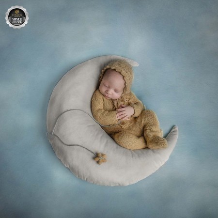 Newborn snuggling into a moon , in yellow and blue tones, taken at Sonia Gourlie Fine art Photography studio 