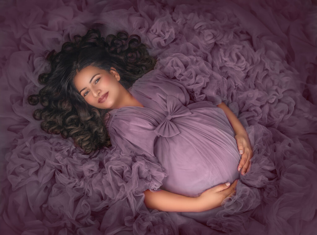 “A pregnant woman wearing a mauve couture gown, lying on her back and gazing up at the camera, with a serene expression on her face.”