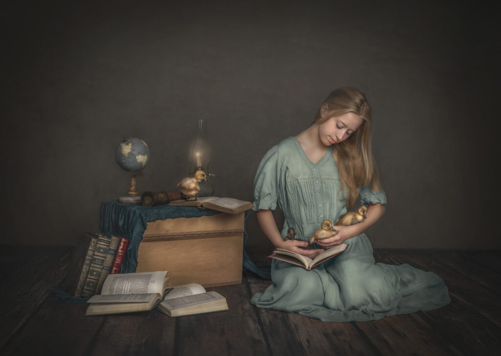 Girl cuddling ducklings while reading a book in a vintage-inspired studio: “A young girl cuddling her new ducklings in a vintage-inspired studio set, while reading them a book, captured by Sonia Gourlie Fine Art Photography in Ottawa, Ontario. The cozy, retro setting adds a warm and charming atmosphere to the scene, highlighting the bond between the girl and her new feathered friends. Ideal for the best photoshoot timings in a serene indoor studio.”