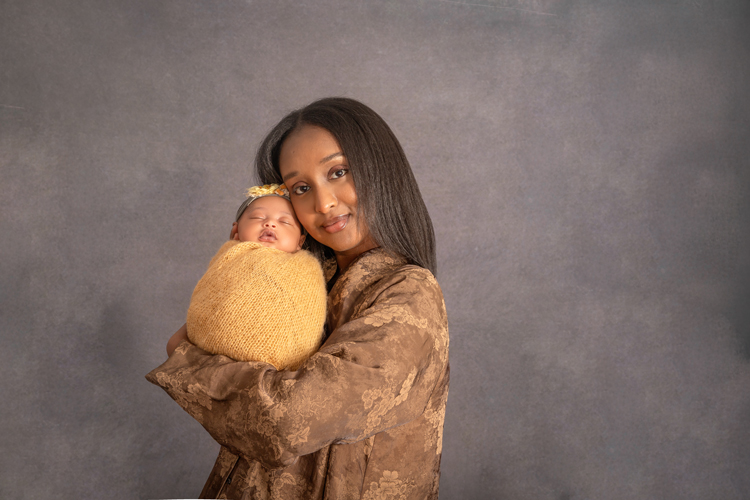 Close-up of mom and newborn girl sharing a tender moment, styled with a brown and yellow  that complements soft pink and lavender tones, captured in Ottawa newborn photography.