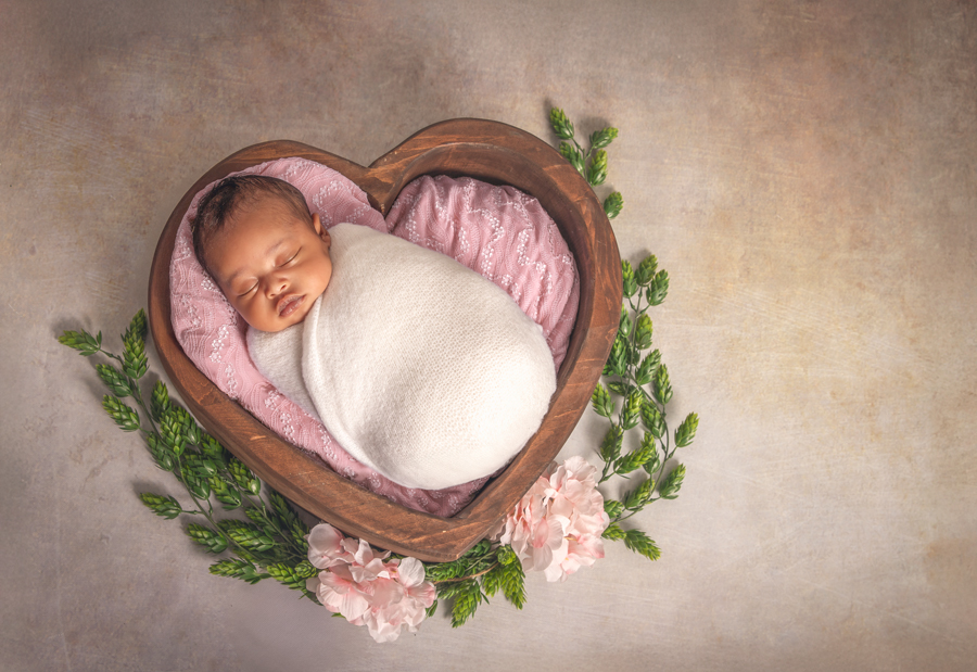 Sleeping newborn girl in a heart-shaped bowl with soft pink and neutral textures, Ottawa newborn session.