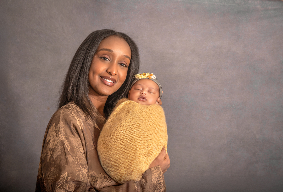 Mom holding her newborn baby girl wrapped in a soft yellow wrap,  during an Ottawa newborn photography session.