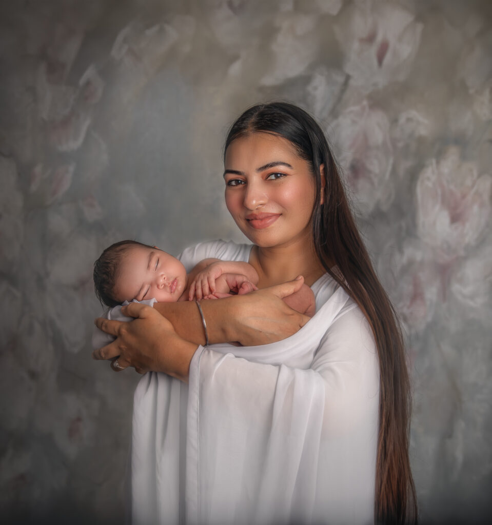 New mom wrapped in soft fabric holding her newborn baby during a studio portrait session in Ottawa