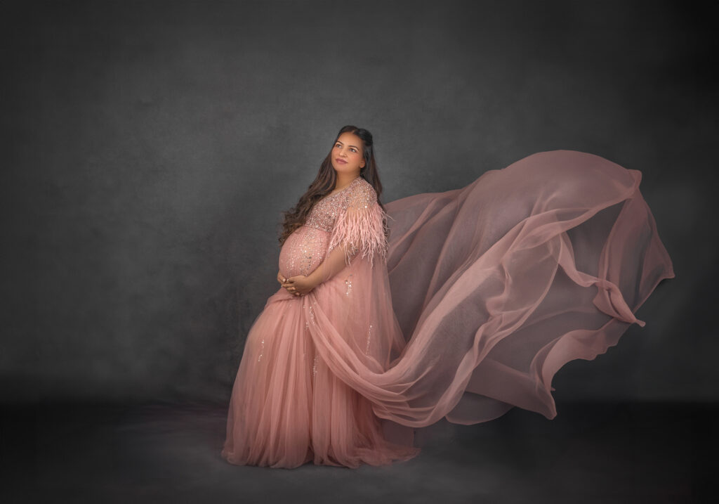 Pregnant woman styled in a sheer  sequence maternity gown with soft lighting during an Ottawa maternity photoshoot
